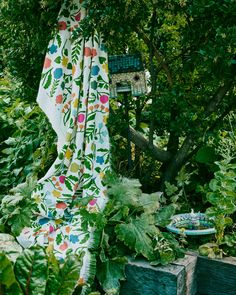 a blanket draped in the middle of a garden with lots of green plants and trees