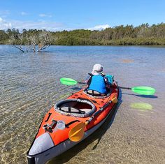 a man in an orange kayak paddling on the water