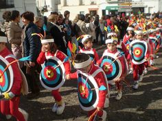 several children in costumes are marching with arrows