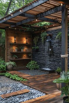 a garden with rocks, plants and lights on the side of an outdoor shower area