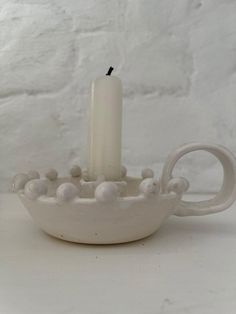 a white candle is sitting in a bowl