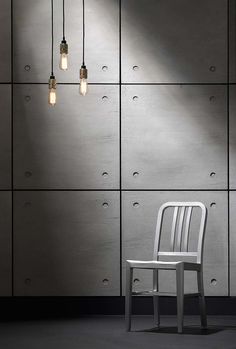 a white chair sitting in front of a wall with three lights hanging from it's sides