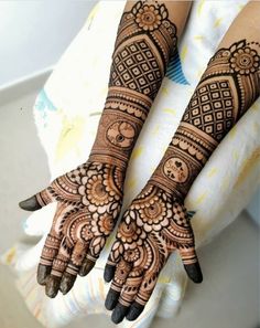 two hands with henna tattoos on them, one is showing the intricate pattern and the other