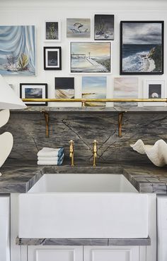 a white sink sitting under pictures on the wall