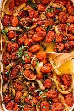 roasted tomatoes and onions in a casserole dish with a wooden spoon on the side