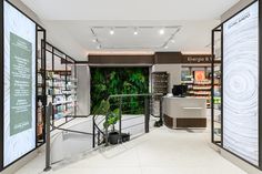 the inside of a pharmacy store with plants and shelves on either side of the door