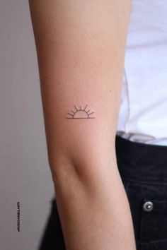 a woman's arm with a small sun tattoo on the back of her left arm