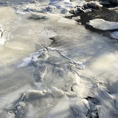 an icy river with ice and snow on the water's edge is seen from above