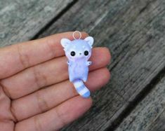 a hand holding a small blue and white cat ornament