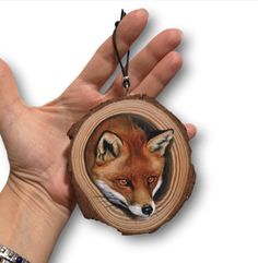 a hand holding a piece of wood with a picture of a red fox on it