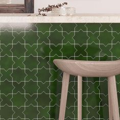 a wooden stool sitting in front of a green tiled wall next to a counter top