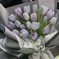 a bouquet of tulips is wrapped in white paper and tied to a car steering wheel