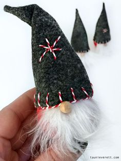 a hand holding a small gnome hat with candy canes on it