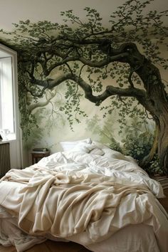 a bedroom with a tree painted on the wall next to a bed and window in front of it