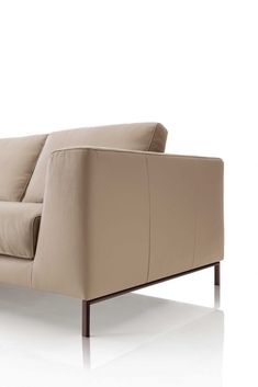 a beige leather couch sitting on top of a white floor next to a wooden frame