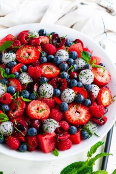 a white bowl filled with berries and kiwis