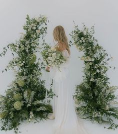 a woman standing in front of flowers and greenery with her back to the camera