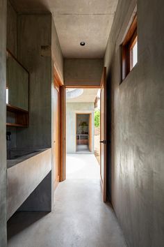 an empty hallway with concrete walls and wood trimming on the door, leading to another room