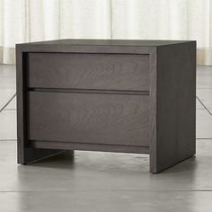 a nightstand with two drawers on top of it in front of a curtained window