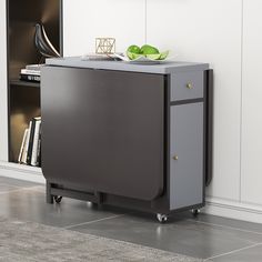 a black and grey cabinet sitting on top of a floor next to a book shelf