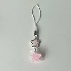 a pink star shaped charm hanging from a lanyard on a white surface with a silver chain