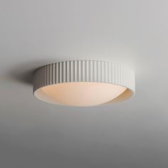 a white ceiling light hanging from the ceiling in a room with grey walls and flooring