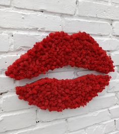 a white brick wall with a red lipstick painted on it's face and surrounded by pom - poms