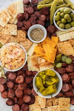 a platter filled with cheese, crackers, olives, and hot dogs