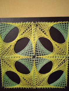 an art piece made out of string and paper with green circles in the center, on a black background