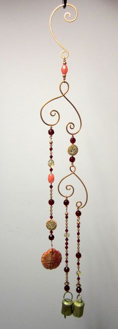 a wind chime with bells and beads hanging from it's side on a white wall