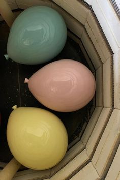 three different colored balloons sitting in a bowl