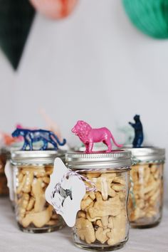 three glass jars filled with different types of nuts and animals on top of a table