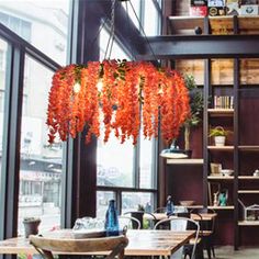 an orange chandelier hangs from the ceiling in a restaurant with tables and chairs