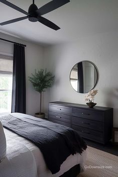 a bedroom with a bed, dresser and ceiling fan in the middle of the room