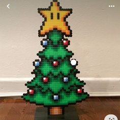 a christmas tree made out of legos on top of a wooden floor next to a wall