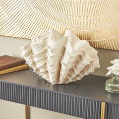 a vase with white flowers on top of a table next to a book and some books