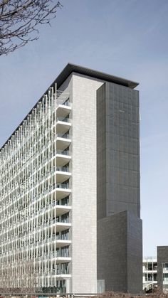 a tall building with lots of windows next to a body of water in front of it