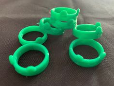 three green plastic rings sitting on top of a black cloth next to two smaller ones