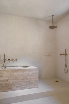 a bathroom with a sink, shower head and two faucets on the wall