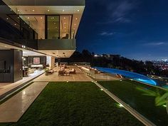 an outdoor living room and dining area at night with lights on the grass in front of it