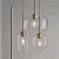 three clear glass pendant lights hanging from a ceiling fixture in a room with white walls