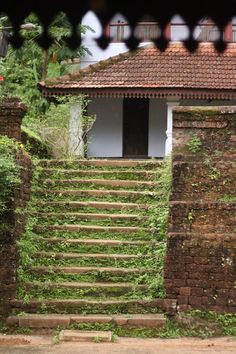 an old brick building with steps leading up to the top and bottom, surrounded by greenery