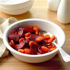 a white bowl filled with beets and carrots on top of a wooden table