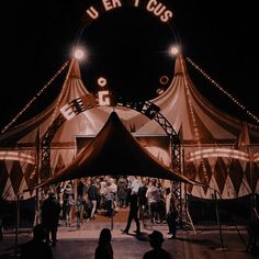 people are standing under a tent at night