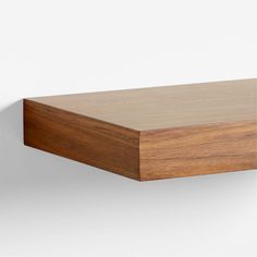 a close up of a wooden shelf against a white wall