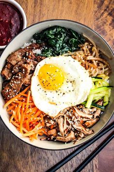 a bowl filled with meat, vegetables and an egg