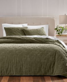 a bed with green bedspread and white pillows