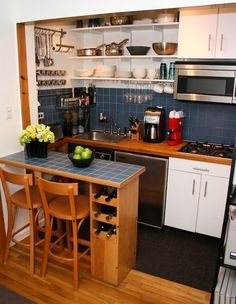 a small kitchen with wooden floors and blue tile backsplash, white cabinets and stainless steel appliances