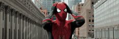 a man in a spider - man suit is walking down the street with his hands on his head