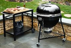 an outdoor bbq grill next to a table with food on it